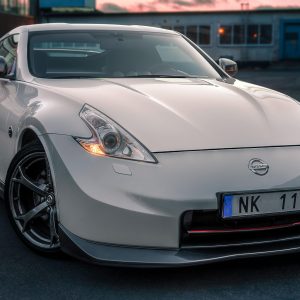 A white Nissan 370Z sports car parked in an urban setting in Norrtälje, Sweden.