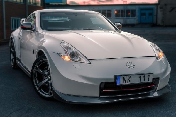 A white Nissan 370Z sports car parked in an urban setting in Norrtälje, Sweden.